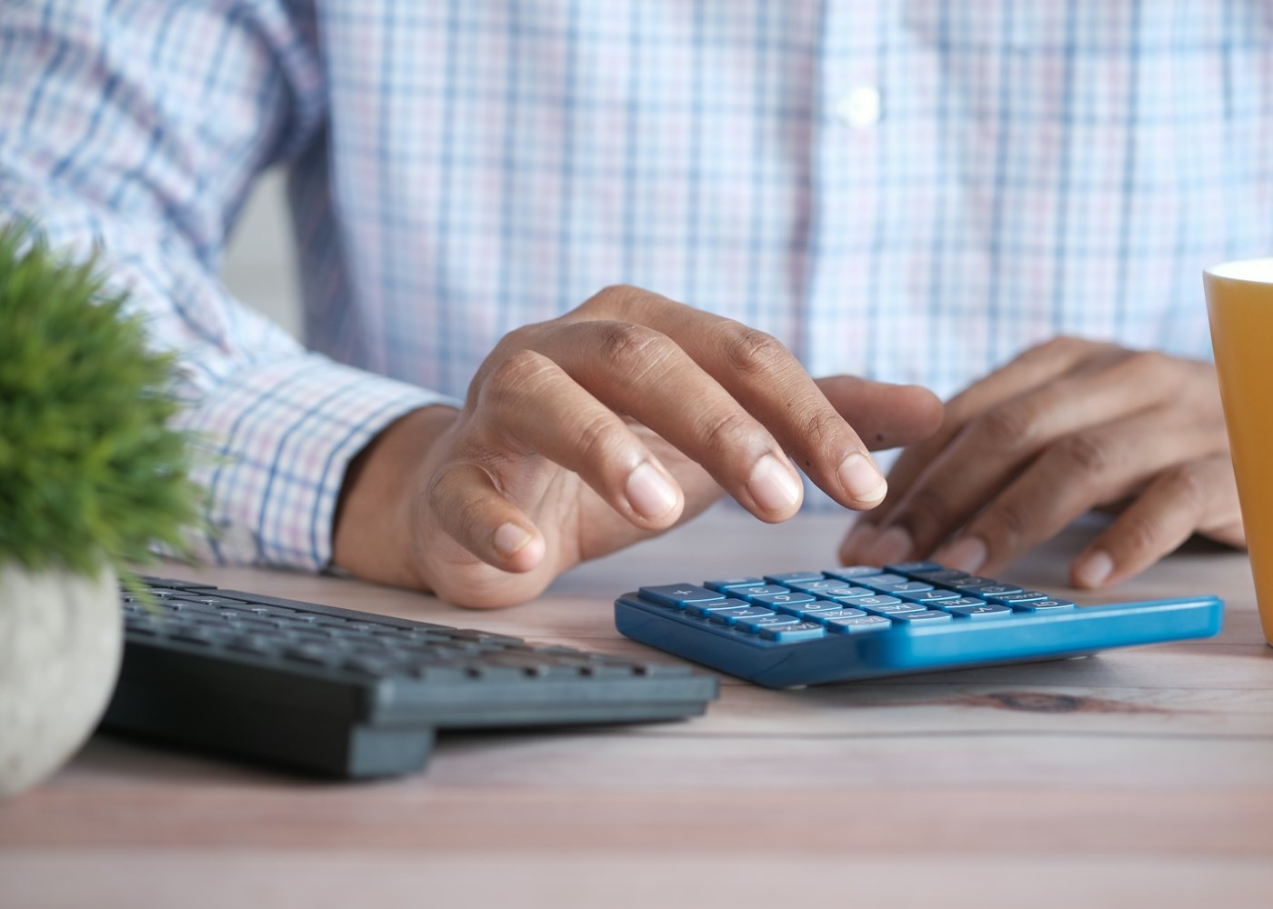 Hands using a calculator next to a laptop