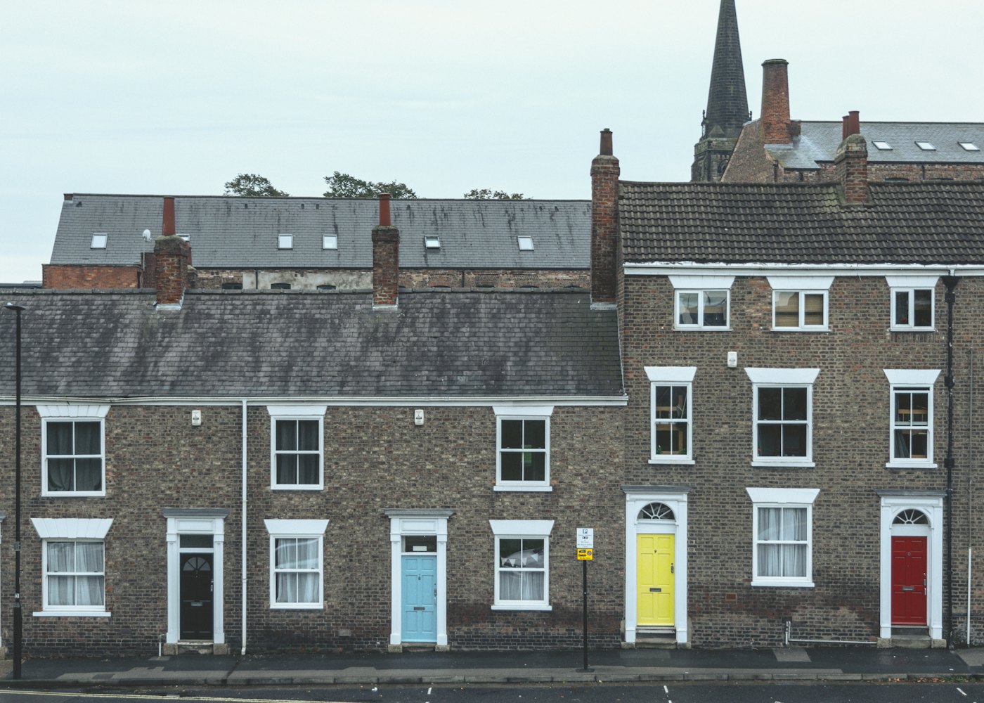 Row of red-brick terraced houses with coloured front doors